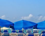 spiaggia attrezzata con ombrelloni blu e cielo sereno