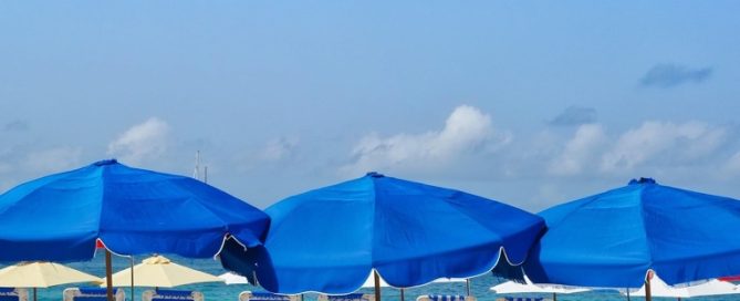 spiaggia attrezzata con ombrelloni blu e cielo sereno